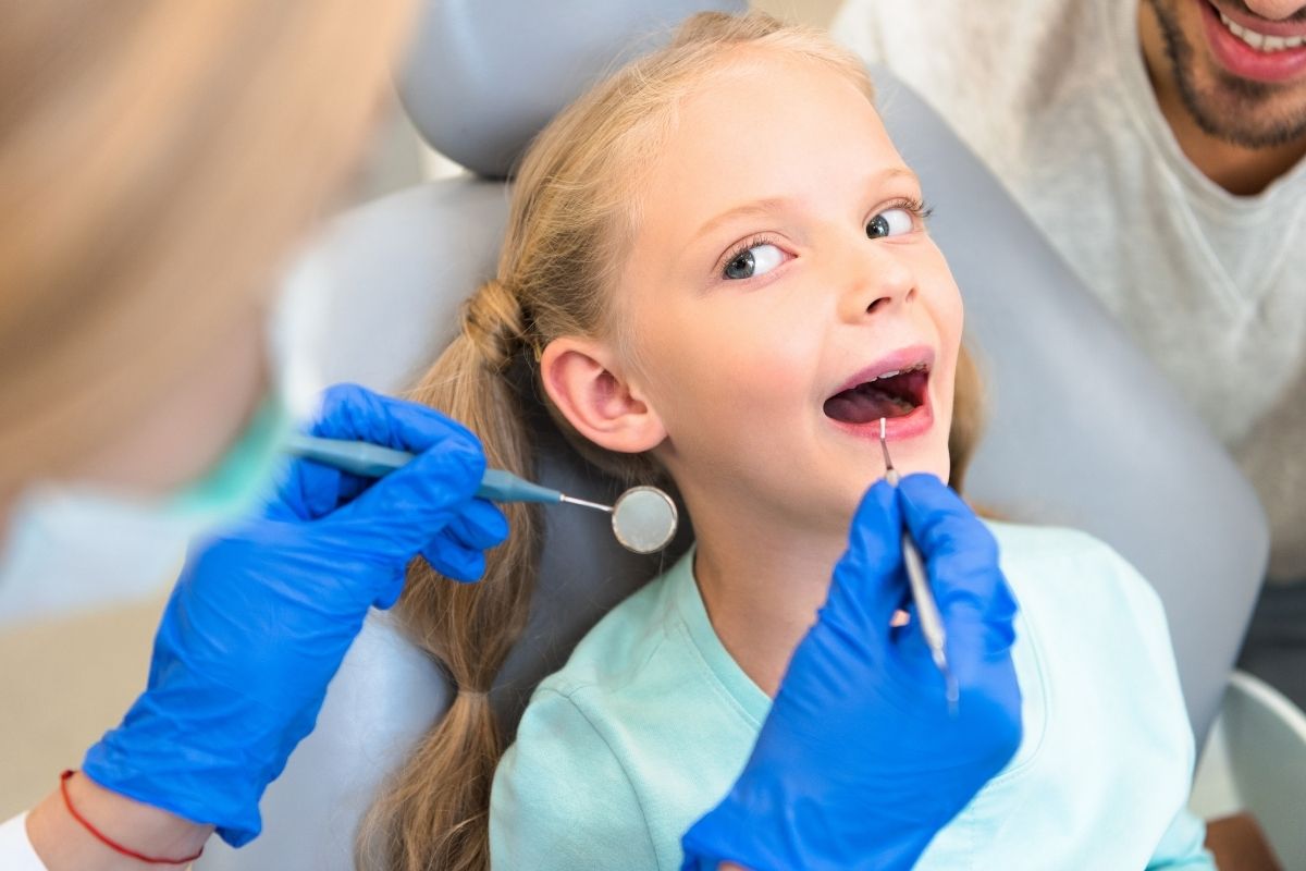 female-dentist-examining-teeth-of-kid